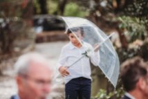 A boy stands under an umbrella before the wedding ceremony