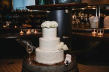 Wedding cake sitting on wine barrels at the wedding reception