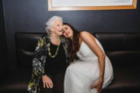 A bride rests her head on her nan's shoulder during the reception