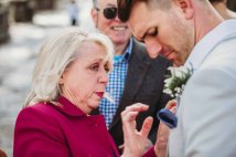 The mother of the groom pins a button flower on the groom